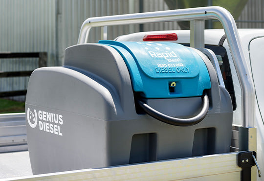 A Genius Diesel Rapid Diesel Only tank mounted on the back of a white utility truck, showing the gray container and bright blue top lid.