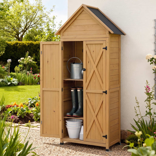 A small wooden garden storage cabinet with a pitched roof, shown outdoors beside a white wall. The cabinet has two doors, one open, revealing shelves with a metal bucket, green rain boots, and white buckets.